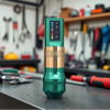 Green and gold wireless tattoo pen standing on a workbench with an LED control panel for adjusting voltage from 5V to 12V.